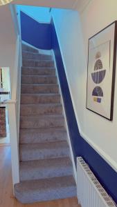 a stairway with blue walls and a blue stair case at Cozy Room in London in Plumstead