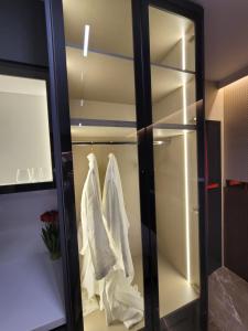 un armario de cristal con ropa blanca colgando en él en La Mirage Suites & Apartments, en Tirana 118 fotos más