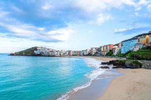 a beach with buildings and the ocean on a cloudy day at Apartamento Catuxa in Malpica
