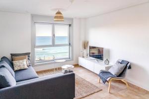 a living room with a couch and a view of the ocean at Apartamento Catuxa in Malpica