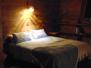 een slaapkamer met een bed met witte lakens en kussens bij Raglan's Tranquil Garden Retreat - Moa Stone Lodge in Raglan