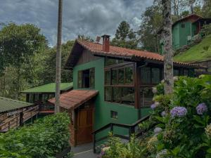 a green house with a green roof at Pousada Recanto do Escorrega in Visconde De Maua