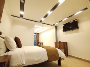 a bedroom with a bed and a flat screen tv at Airos Hotel in Baños