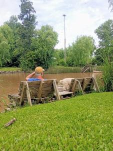 a person sitting on a bench in the water at Quinta llamame antigua in Tigre