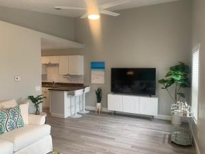 uma sala de estar com um sofá branco e uma televisão de ecrã plano em Tropical Haven em Panama City Beach