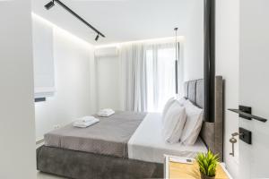 a bedroom with a bed with white walls and a window at Varkiza Luxury Suites by Raise in Vari
