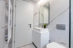 a white bathroom with a sink and a mirror at Varkiza Luxury Suites by Raise in Vari