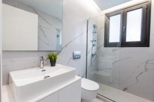 a white bathroom with a sink and a toilet at Varkiza Luxury Suites by Raise in Vari
