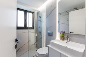 a bathroom with a sink and a toilet and a shower at Varkiza Luxury Suites by Raise in Vari