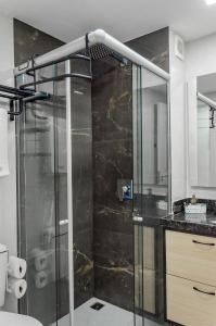 um chuveiro com uma porta de vidro na casa de banho em Suíte PÉ NA AREIA com PISCINA, WIFI e ESTACIONAMENTO em PONTA NEGRA em Natal