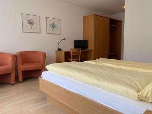 a bedroom with a bed and two chairs and a desk at Hotel Rebstock Meiringen in Meiringen