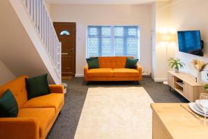 ein Wohnzimmer mit zwei orangefarbenen Sofas und einem Fernseher in der Unterkunft Modern cottage WiFi Free Parking in Penwortham