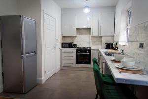 a kitchen with white cabinets and a stainless steel refrigerator at Saxon House, sleeps 5, free parking in London