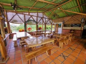 - un coin repas avec des tables et des bancs en bois dans un pavillon dans l'établissement Chalet Familiar con Piscina, à Armenia