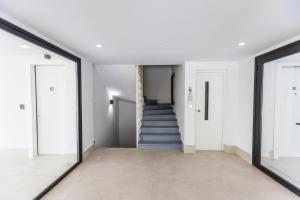 a hallway with white walls and a staircase with doors at Varkiza Luxury Suites by Raise in Vari