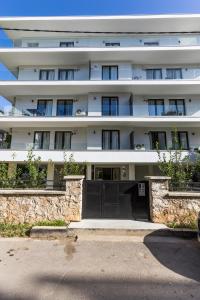 a white building with a black gate in front of it at Varkiza Luxury Suites by Raise in Vari