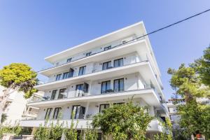 a white building with trees in front of it at Varkiza Luxury Suites by Raise in Vari