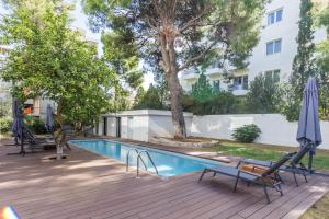 una piscina con sedie e ombrellone su una terrazza di Varkiza Luxury Suites a Vari