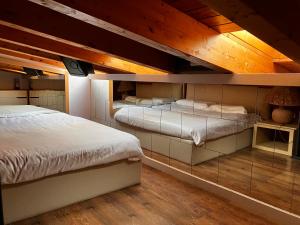 Duas camas num quarto com tectos em madeira em A&A Rooftop em Somma Lombardo