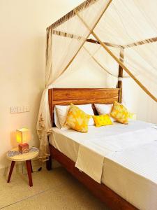 a bedroom with a bed with yellow and white pillows at Swallow villa - French guest house in Ahangama