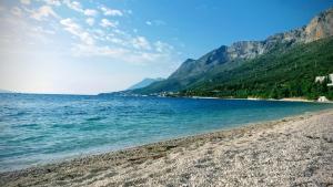 a beach with blue water and mountains in the background at Apartman Victoria in Gradac