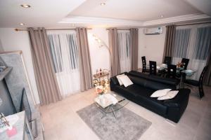 uma sala de estar com um sofá preto e uma mesa em JQ Apartments em Acra
