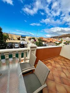 a balcony with a glass table and chairs on a roof at Elegant Palm Mar Apartment in Palm-Mar