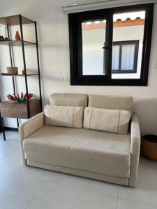 a couch in a living room with a window at Eita Bahia in Praia do Forte