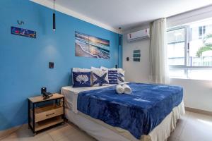 um quarto com paredes azuis e uma cama com toalhas em Suíte PÉ NA AREIA com PISCINA, WIFI e ESTACIONAMENTO em PONTA NEGRA em Natal