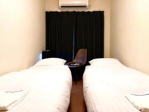 Habitación con 2 camas y una silla. en Hotel&Co. Sagami, en Tokio