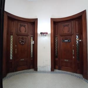 dwa drewniane drzwi w pokoju ze ścianą w obiekcie Kalahat w BuenosAires