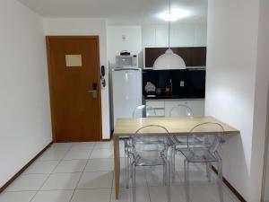 バーハ・デ・サン・ミゲウにあるApartamento Iloa residenceのキッチン(テーブル、椅子、冷蔵庫付)