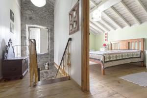 una camera con un letto in una stanza con un muro in pietra di Casa dos Platanos-Family Home a Sete Cidades