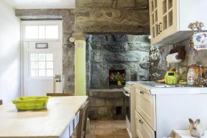 uma cozinha com uma parede de pedra e um fogão forno superior em Casa dos Platanos-Family Home em Sete Cidades