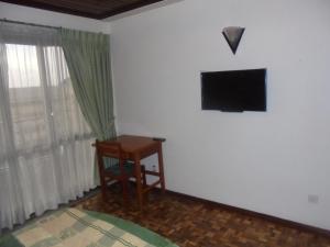 a room with a desk and a television on the wall at Weygoss Guest House in Addis Ababa