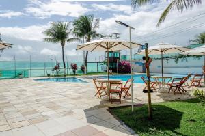a patio with tables and umbrellas next to a pool at Beachfront Suite with Pool, WIFI and Parking in Ponta Negra in Natal
