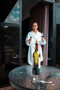 聖拉斐爾的住宿－Gaia Glamping Elegancia Escarlata estándar 1，穿着白色长袍的女人,拿着一瓶葡萄酒