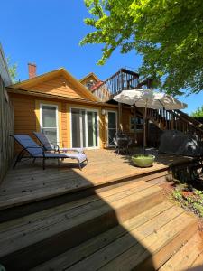 a wooden deck with two chairs and an umbrella at NE Portland Oregon Modern Victorian Duplex in Portland