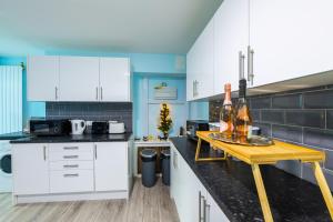 a kitchen with white cabinets and a table with wine bottles at Heart of Maidstone - Premium Double Rooms with FREE Wi-Fi in Maidstone