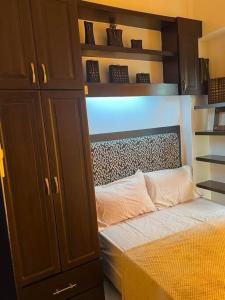 a bedroom with a bed and a cabinet and shelves at Elegant Cozy 2BR Near The Airport in Manila
