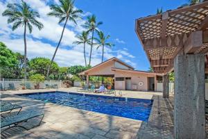 een zwembad met palmbomen en een huis bij Kihei Akahi C-608 - Stunning Ocean Views, AC! in Wailea