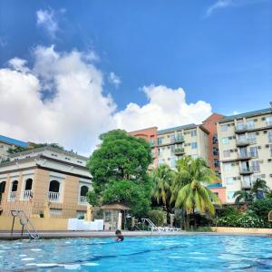 a person in a swimming pool in front of buildings at Elegant Cozy 2BR Near The Airport in Manila