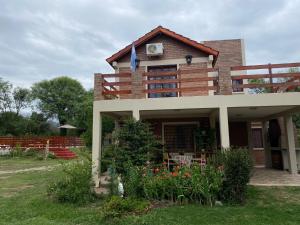 una casa con balcón y flores en el patio en CABAÑAS MIS SUEÑOS I, en Merlo
