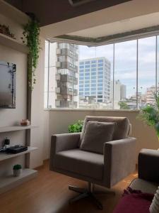 sala de estar con silla y ventana grande en Flat reformado no Piazza Navona en Porto Alegre