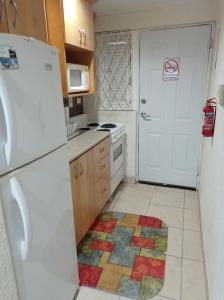 eine Küche mit einem weißen Kühlschrank und einem bunten Teppich auf dem Boden in der Unterkunft 126 Friendship, Rockley Golf Club in Bridgetown