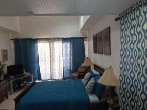 Schlafzimmer mit blauem Bett und blauen Vorhängen in der Unterkunft 126 Friendship, Rockley Golf Club in Bridgetown
