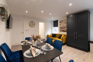 Fantastic New, London Apartment 3 Bed 1 Bath & Parking في Whetstone: غرفة معيشة مع طاولة طعام وكراسي زرقاء