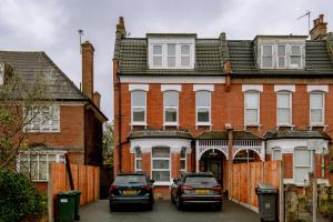 two cars parked in front of a brick house at Fantastic New, London Apartment 3 Bed 1 Bath & Parking in Whetstone