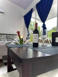 una botella de vino sentada en una mesa con dos copas de vino en Hotel Serendipity, en Tortuguero