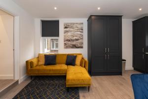 Fantastic New, London Apartment 3 Bed 1 Bath & Parking في Whetstone: غرفة معيشة مع أريكة صفراء وخزانة سوداء